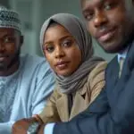 i want an image showing 3 africans sitting sitting around a table one man wearing boubou, one woman with hijab and one man wearing suit. all 3 are experts and consultants facing us.