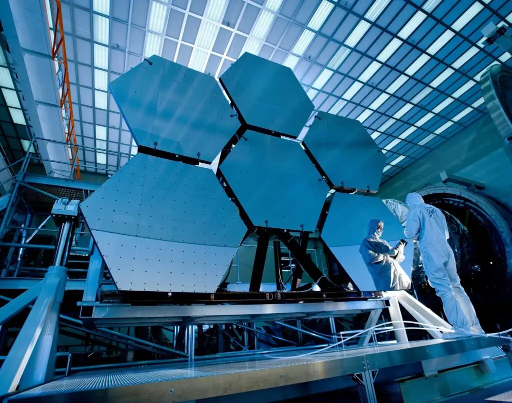 Accueil Engineers in protective suits work on telescopic mirrors in a high-tech lab.